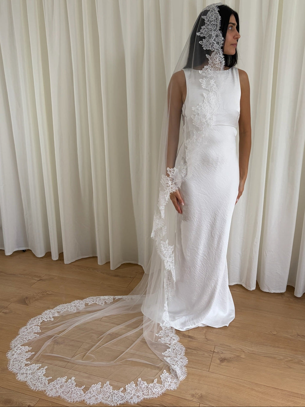 Soft off-white chapel bridal veil made from lightweight tulle with delicate lace trim along the edges for a dreamy, romantic look