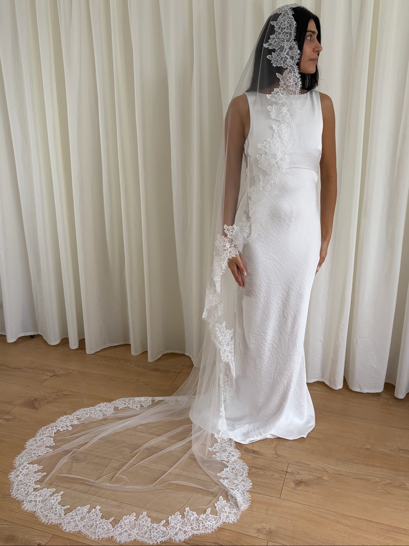 Soft off-white chapel bridal veil made from lightweight tulle with delicate lace trim along the edges for a dreamy, romantic look
