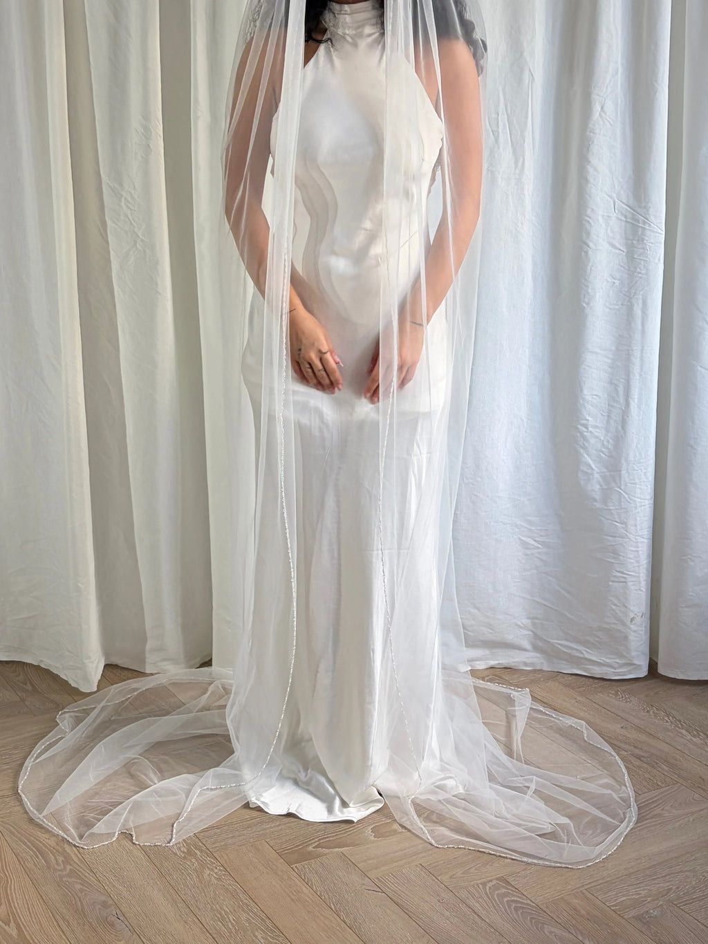 The Cathedral-Length Pearl Trim Veil features soft tulle and pearls & beads for a timeless, romantic bridal look. Lightweight and ethereal, it drapes beautifully for a graceful, luminous finish — perfect for modern or classic brides. The cloak-like full length veil finish is perfcet for the ethreal look.