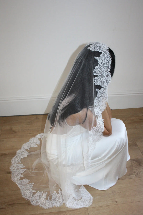 Soft off-white chapel bridal veil made from lightweight tulle with delicate lace trim along the edges for a dreamy, romantic look