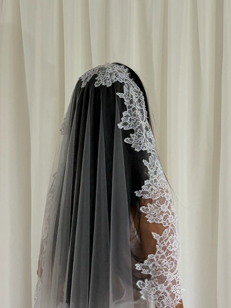 Soft off-white chapel bridal veil made from lightweight tulle with delicate lace trim along the edges for a dreamy, romantic look