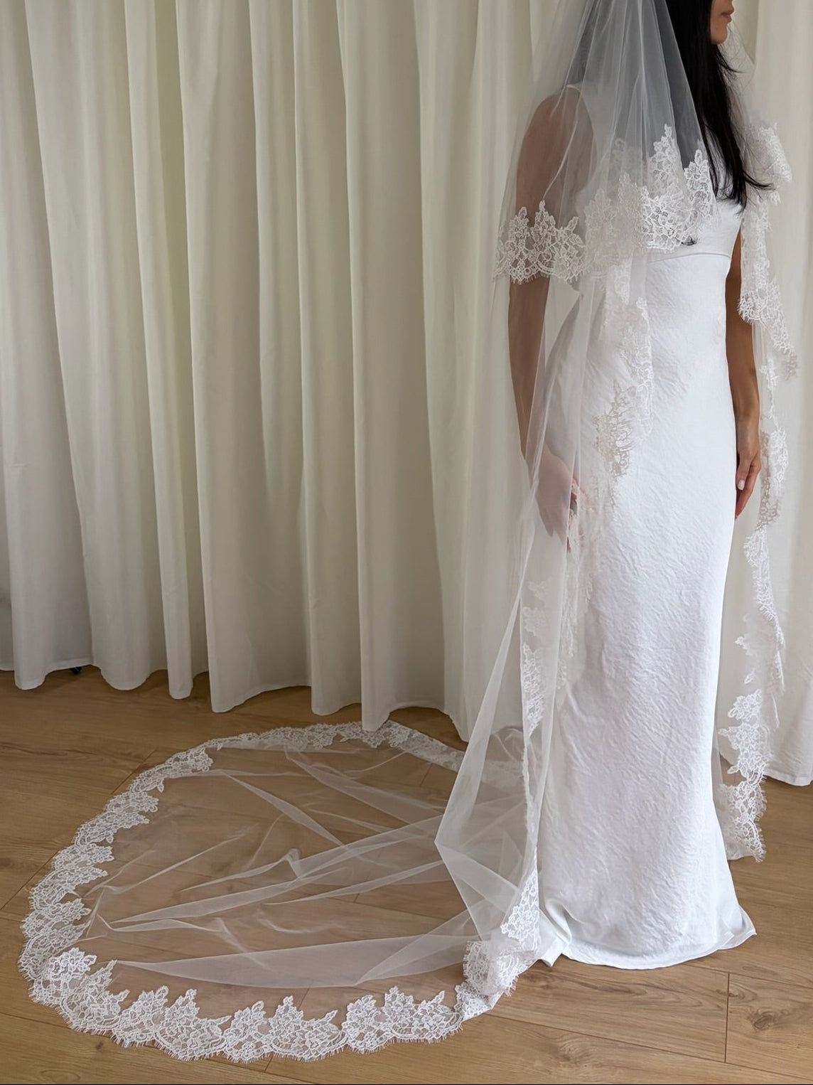 Soft off-white cathedral bridal veil made from lightweight tulle with delicate lace trim and a drop blusher, perfect for a dreamy, romantic look