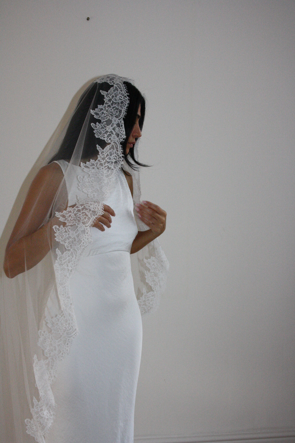 Soft off-white chapel bridal veil made from lightweight tulle with delicate lace trim along the edges for a dreamy, romantic look