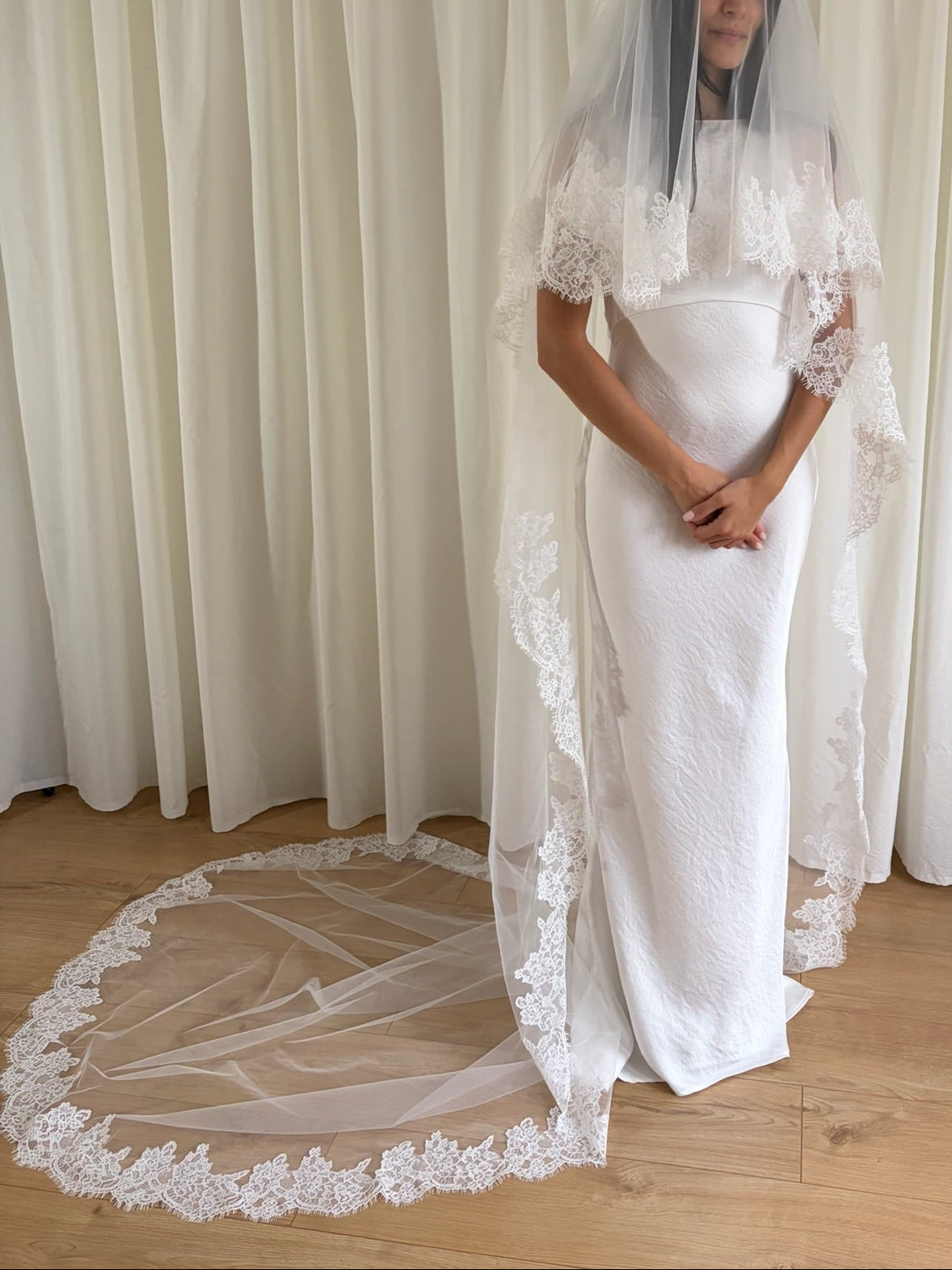 Soft off-white cathedral bridal veil made from lightweight tulle with delicate lace trim and a drop blusher, perfect for a dreamy, romantic look