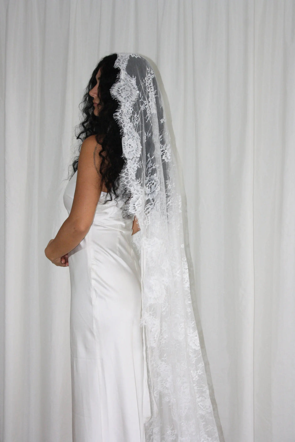 The Mantilla-Style Chantilly Rose Full Lace Veil is a cathedral-length bridal statement piece, designed for timeless elegance. Made from soft, lightweight tulle, it features intricate Chantilly rose lace that frames the veil completely, creating a delicate, romantic finish. The veil drapes beautifully straight to the ground, evoking a graceful, ethereal silhouette.This a vintage take on spanish style mantilla veil.