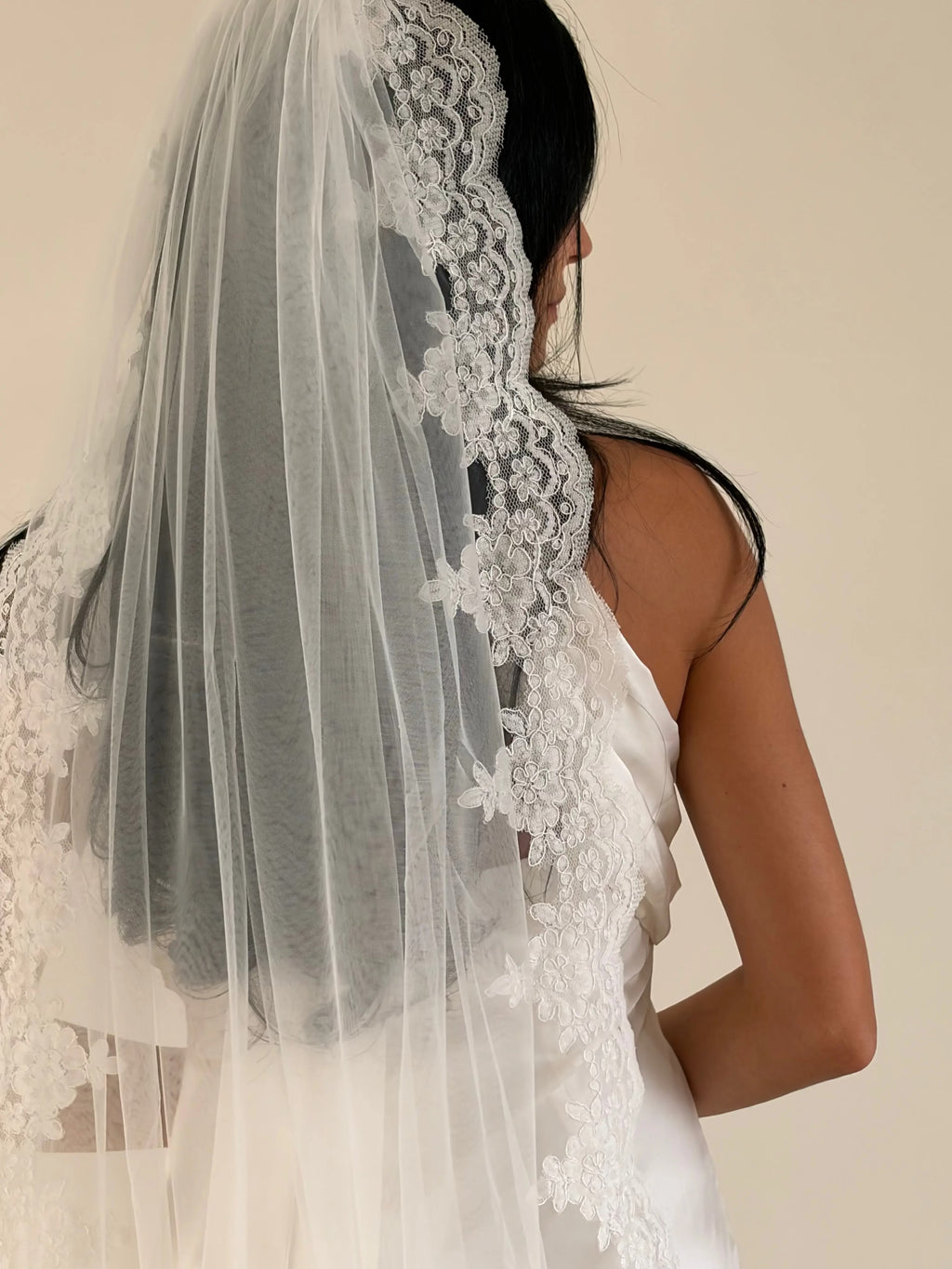 Lace trim bunched mantilla veil combines cathedral-length drama with hauntingly soft elegance. Made from luxurious, lightweight tulle and finished with fine lace edging, it falls straight to the ground in a flowing, cloak-like drape. Designed for brides seeking a romantic and timeless silhouette