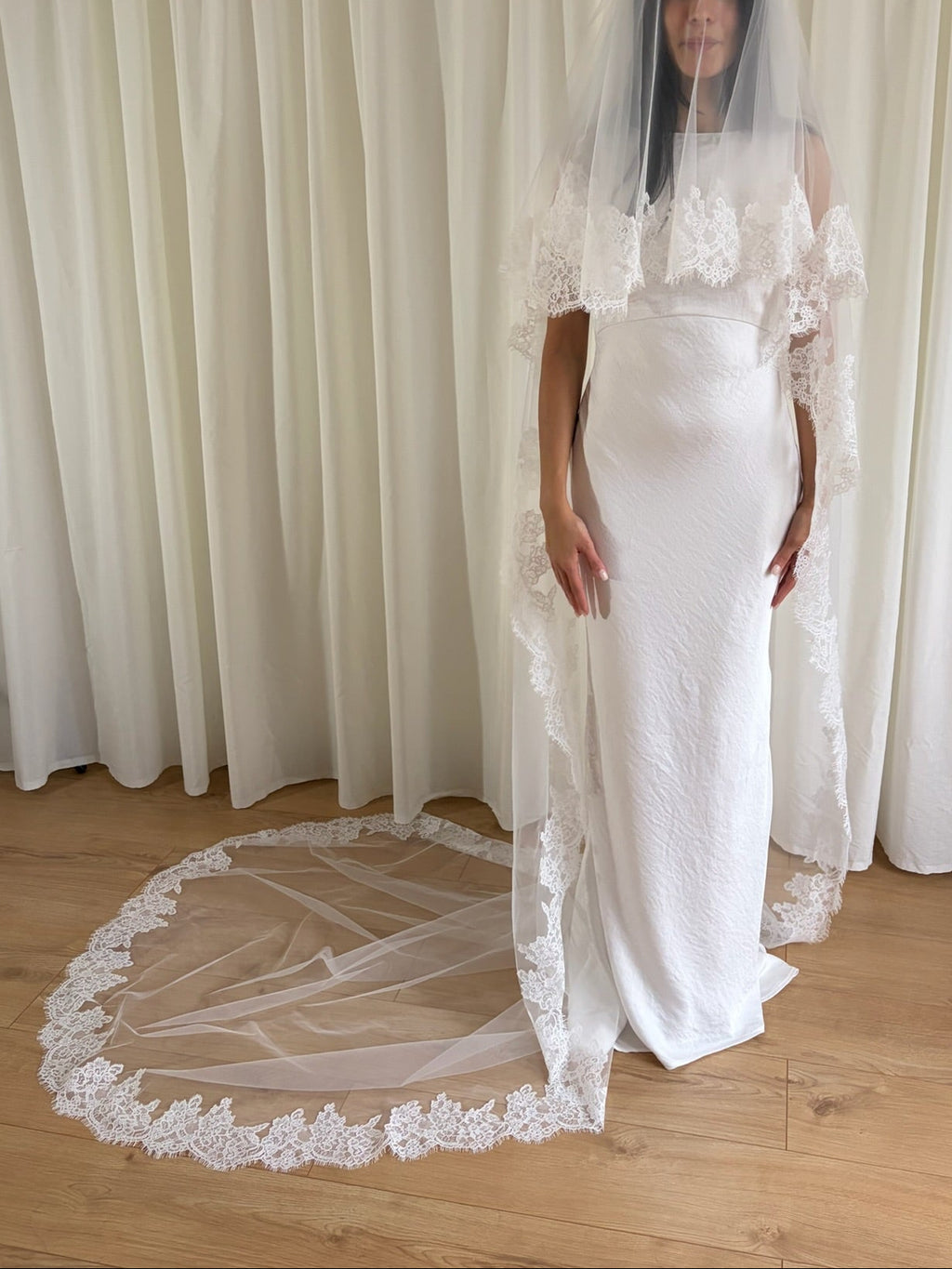 Soft off-white cathedral bridal veil made from lightweight tulle with delicate lace trim and a drop blusher, perfect for a dreamy, romantic look