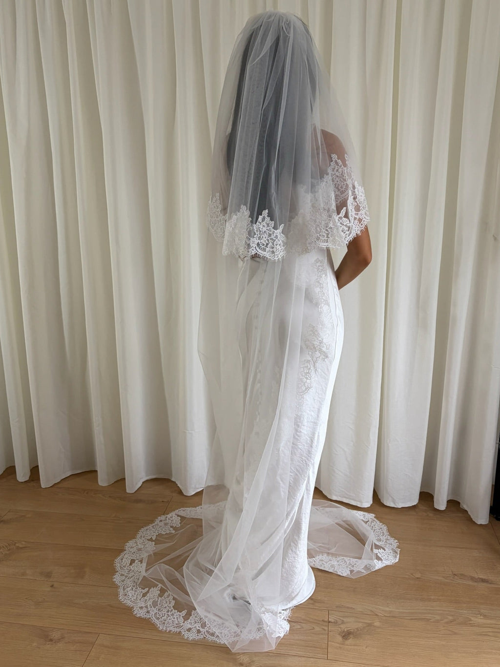 Soft off-white cathedral bridal veil made from lightweight tulle with delicate lace trim and a drop blusher, perfect for a dreamy, romantic look