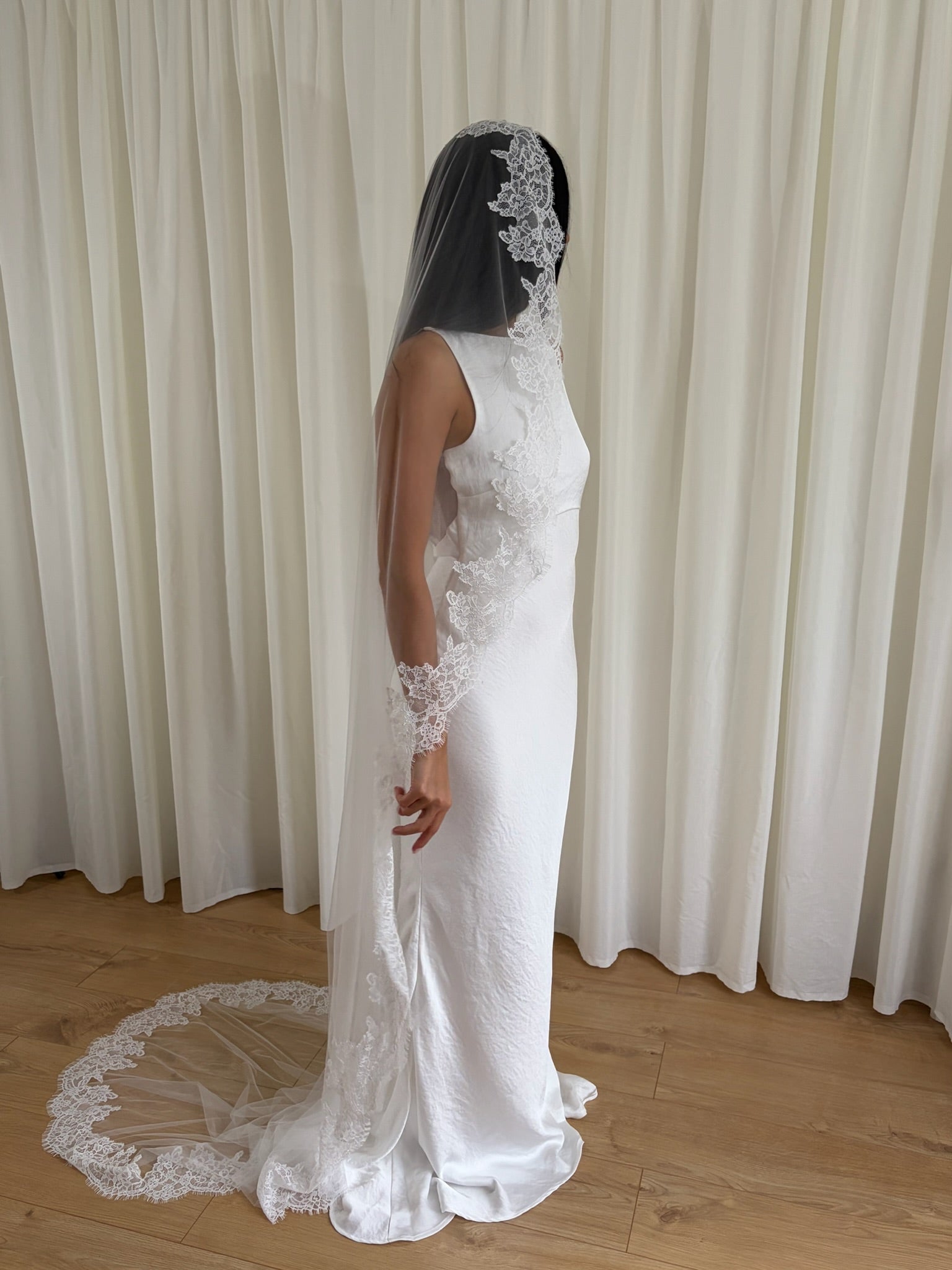 Soft off-white chapel bridal veil made from lightweight tulle with delicate lace trim along the edges for a dreamy, romantic look