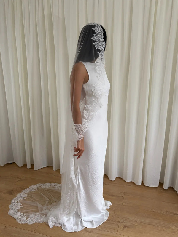 Soft off-white chapel bridal veil made from lightweight tulle with delicate lace trim along the edges for a dreamy, romantic look