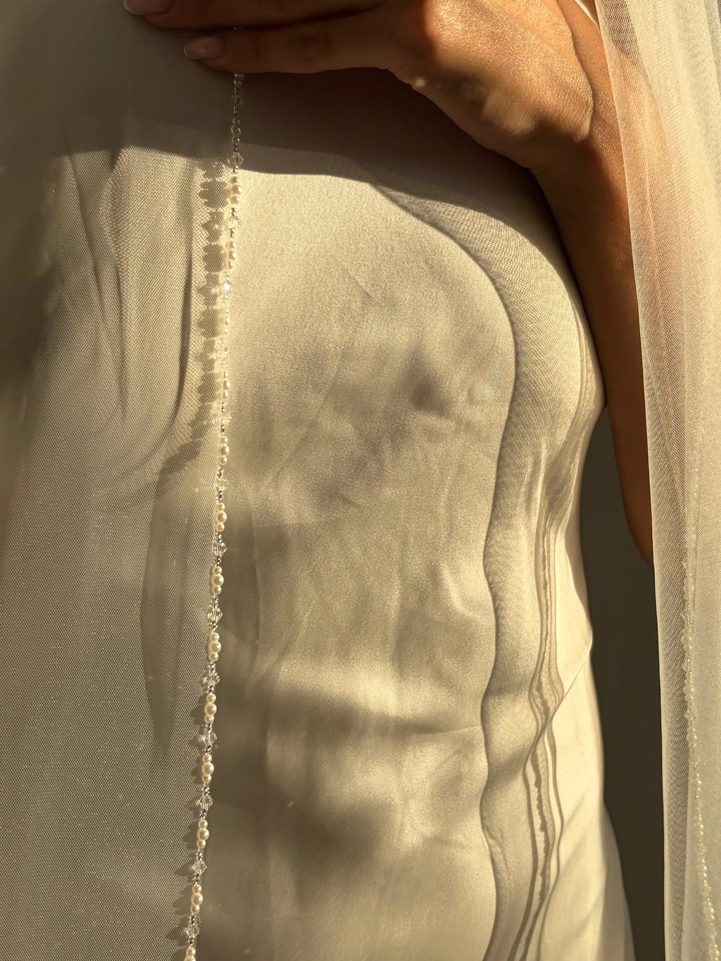 The Cathedral-Length Pearl Trim Veil features soft tulle and pearls & beads for a timeless, romantic bridal look. Lightweight and ethereal, it drapes beautifully for a graceful, luminous finish — perfect for modern or classic brides. The cloak-like full length veil finish is perfcet for the ethreal look.