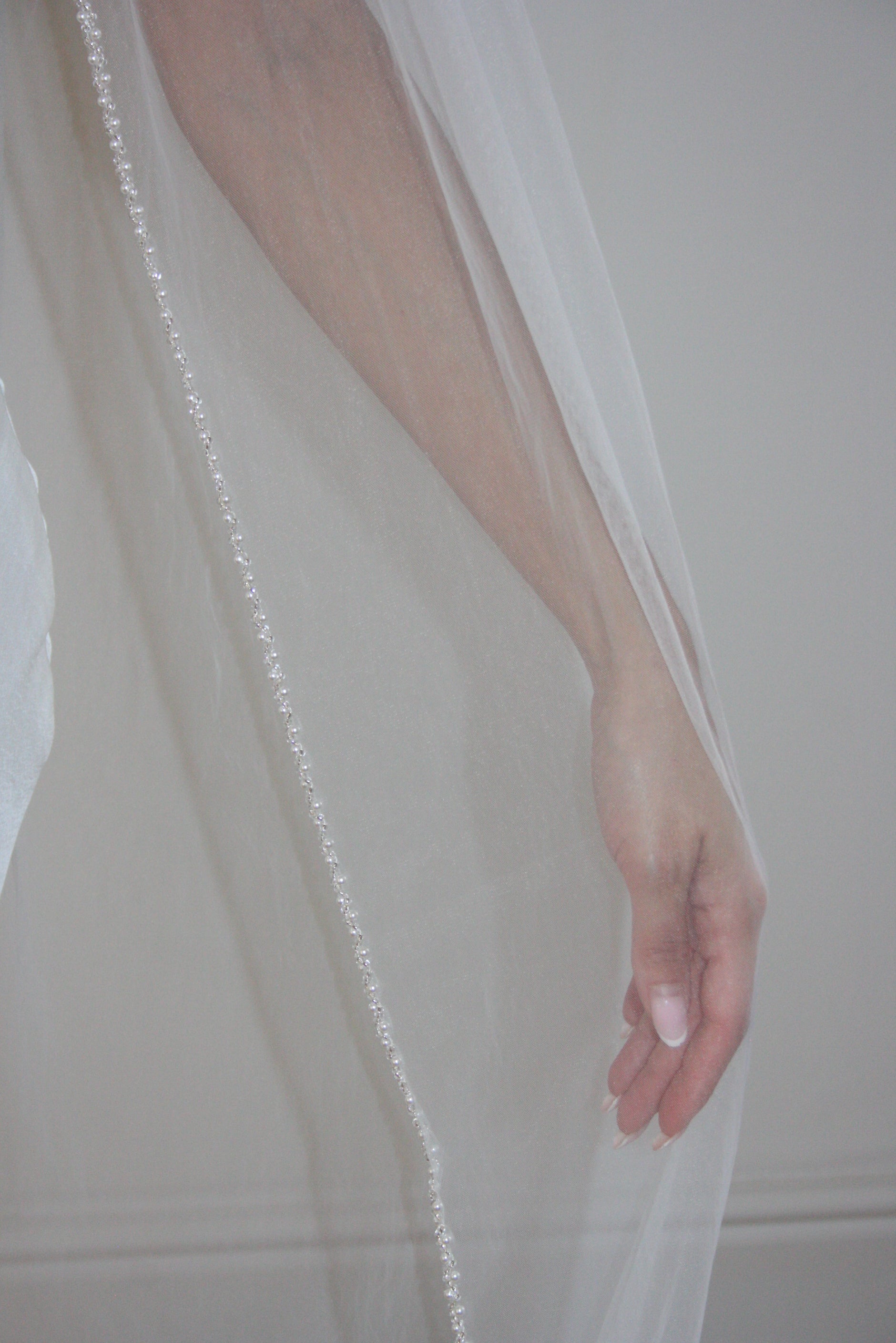 Soft tulle wedding veil with hand-placed pearl trim, perfect for modern and classic brides seeking an elegant bridal accessory