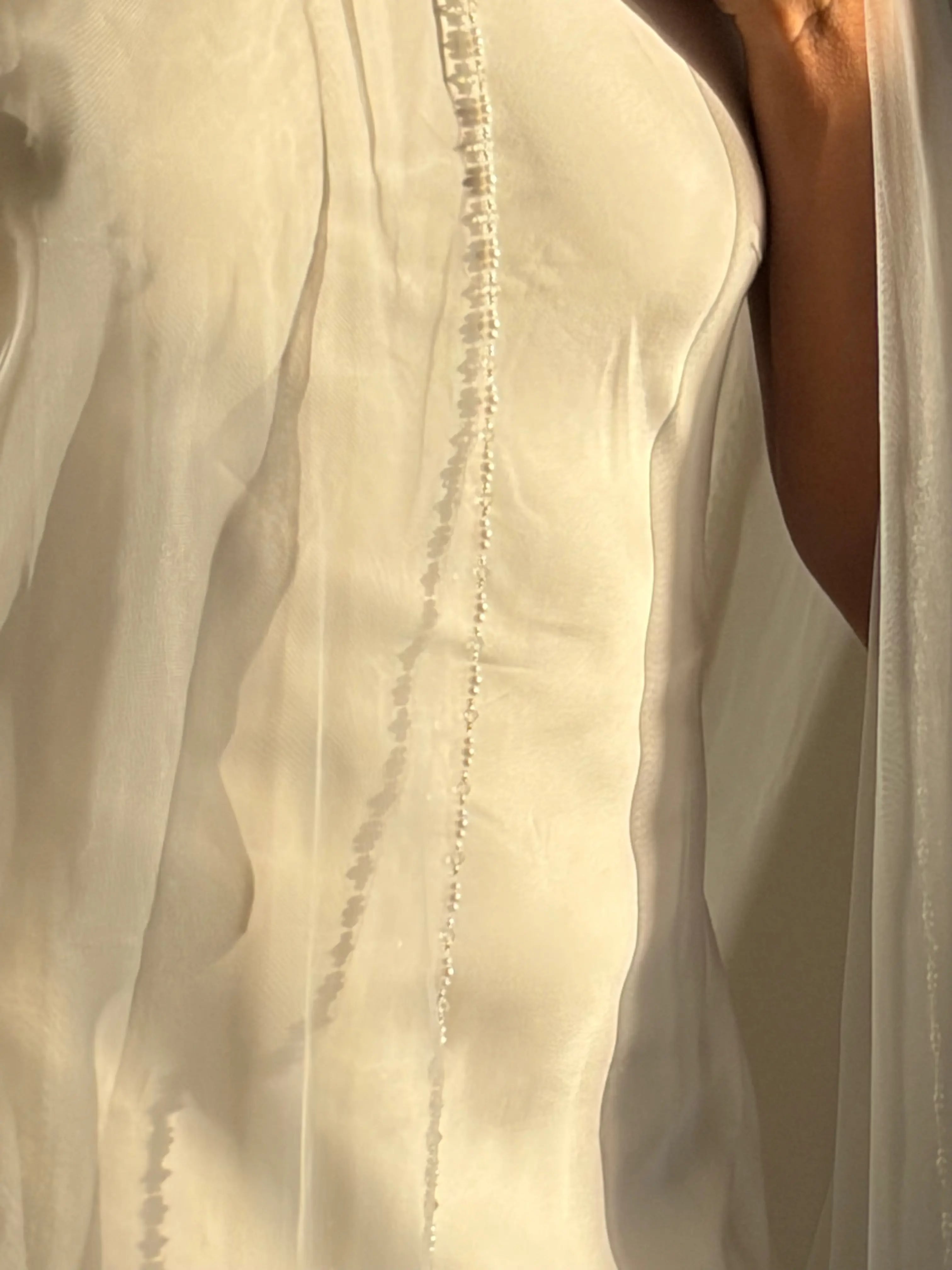 The Cathedral-Length Pearl Trim Veil features soft tulle and pearls & beads for a timeless, romantic bridal look. Lightweight and ethereal, it drapes beautifully for a graceful, luminous finish — perfect for modern or classic brides. The cloak-like full length veil finish is perfcet for the ethreal look.