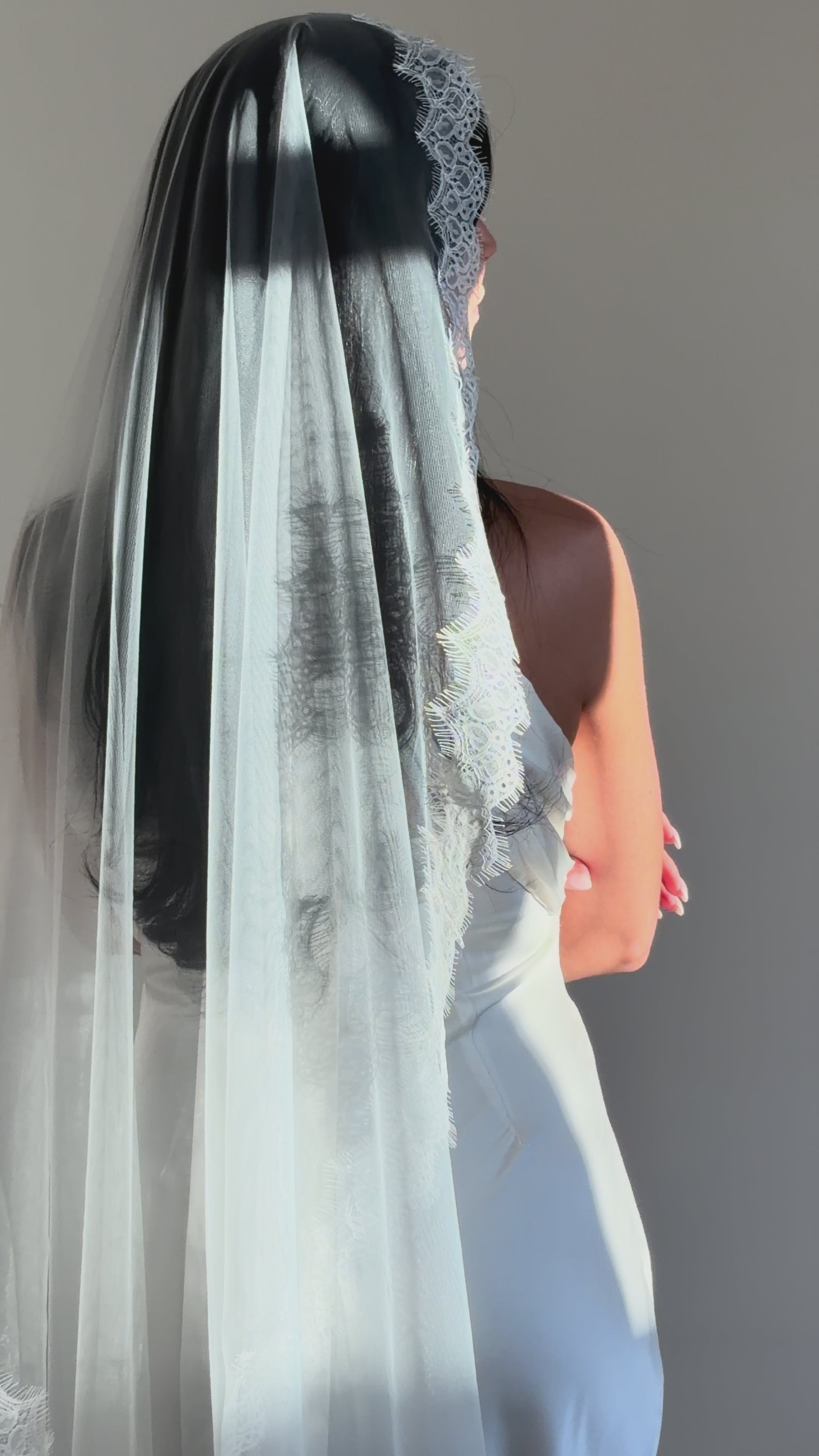 The Mantilla French Chantilly Lace Cathedral-Length Veil captures the romance of classic bridal style with exquisite craftsmanship and detail. Made from fine, lightweight tulle, this single-tier veil is bordered with intricate French Chantilly floral lace, complete with delicate eyelash edging that adds soft texture and movement. Its cathedral length creates a graceful, dramatic silhouette perfect for traditional or contemporary gowns. A hidden comb ensures a secure, comfortable hold, letting the veil flow 