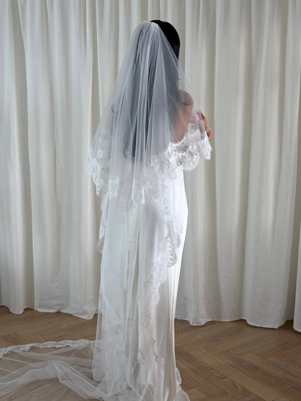 The Eyelash Trim Blusher Veil is a light, romantic accessory for modern brides seeking an ethereal finishing touch. Made from soft, flowing tulle, it features delicate eyelash lace along the edge for a subtle, feminine detail. The veil drapes softly over the face and shoulders, enhancing the bride’s silhouette with an airy, graceful effect. Its discreet comb attachment ensures a secure, seamless fit, making it ideal for both ceremony and photography. Perfect for adding a classic yet dreamy accent to any gow