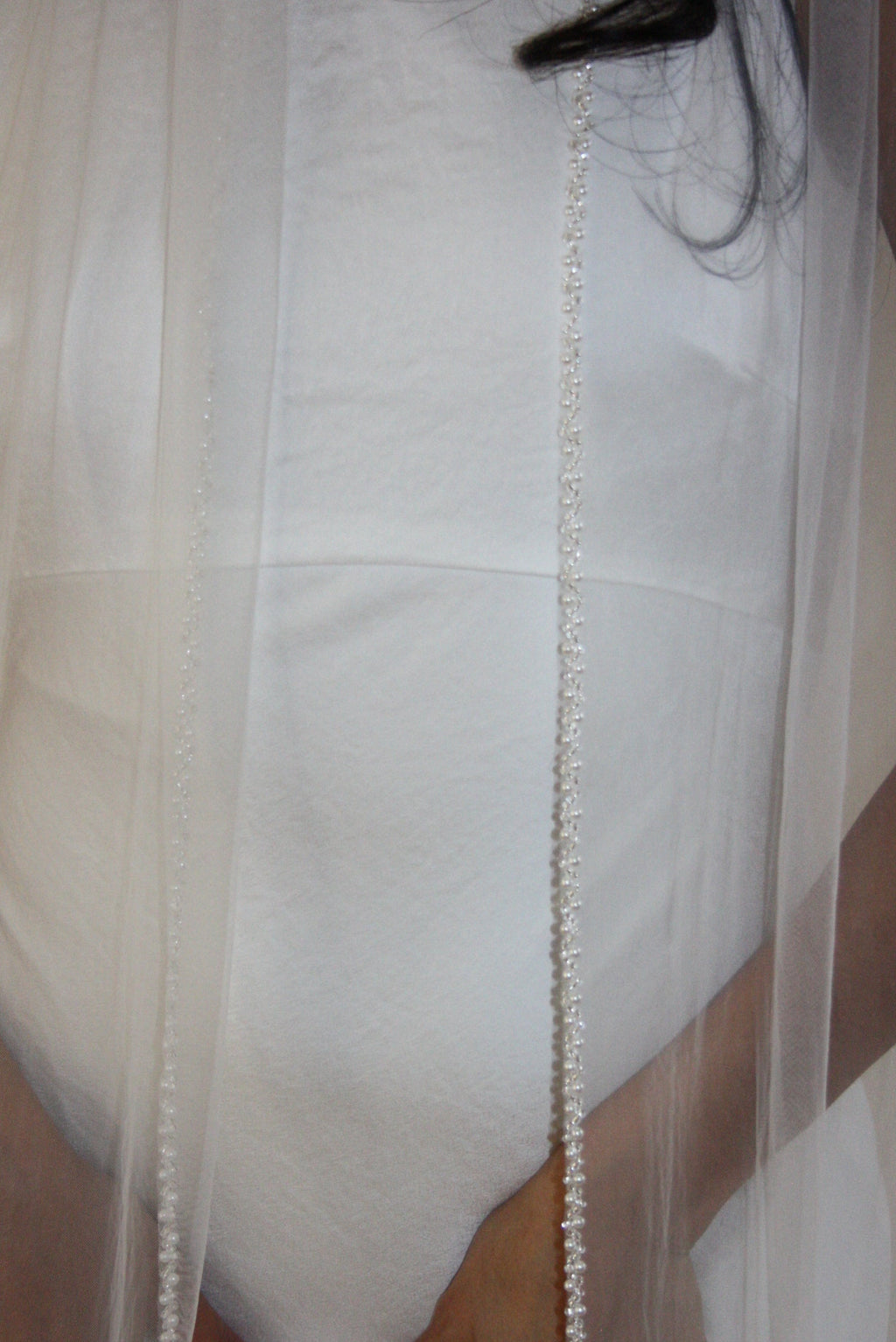 Soft tulle wedding veil with hand-placed pearl trim, perfect for modern and classic brides seeking an elegant bridal accessory