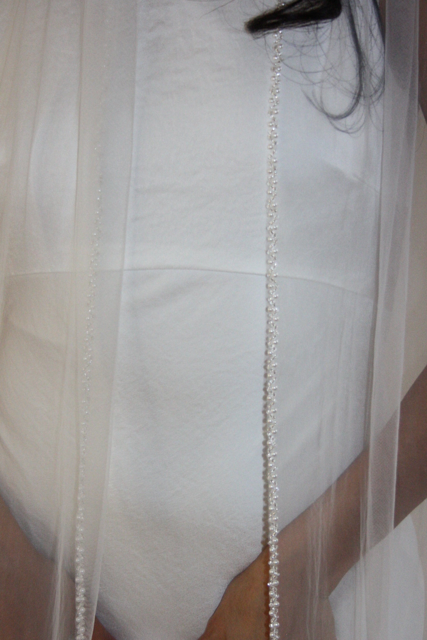 Soft tulle wedding veil with hand-placed pearl trim, perfect for modern and classic brides seeking an elegant bridal accessory