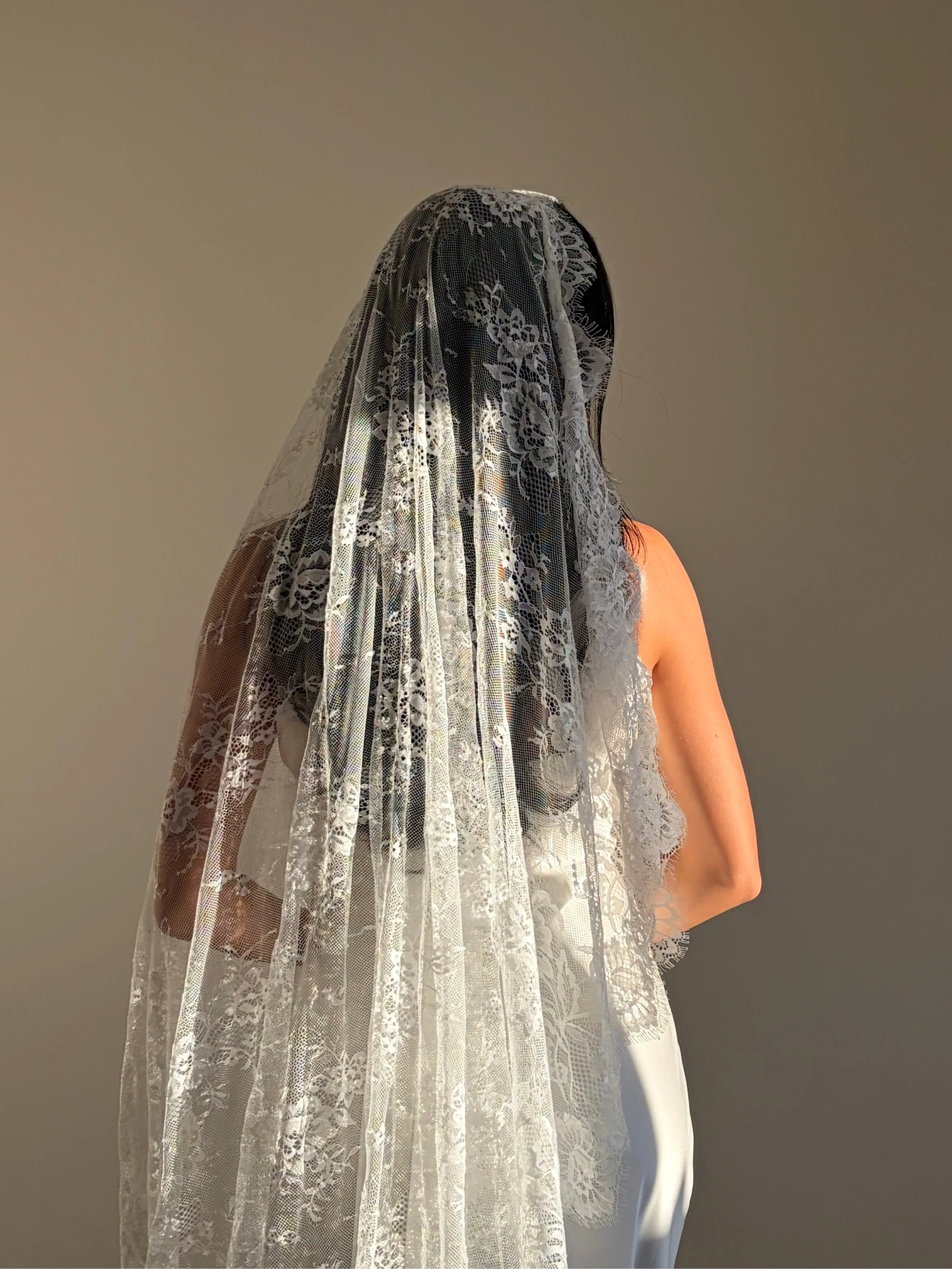 The Mantilla-Style Chantilly Rose Full Lace Veil is a cathedral-length bridal statement piece, designed for timeless elegance. Made from soft, lightweight tulle, it features intricate Chantilly rose lace that frames the veil completely, creating a delicate, romantic finish. The veil drapes beautifully straight to the ground, evoking a graceful, ethereal silhouette.This a vintage take on spanish style mantilla veil.