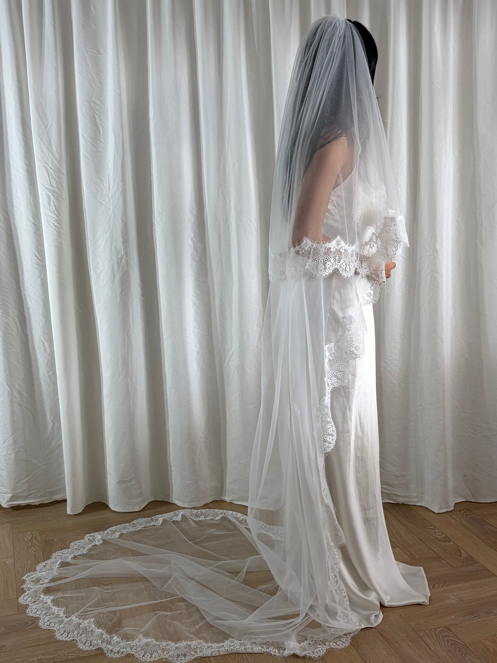 The Eyelash Trim Blusher Veil is a light, romantic accessory for modern brides seeking an ethereal finishing touch. Made from soft, flowing tulle, it features delicate eyelash lace along the edge for a subtle, feminine detail. The veil drapes softly over the face and shoulders, enhancing the bride’s silhouette with an airy, graceful effect. Its discreet comb attachment ensures a secure, seamless fit, making it ideal for both ceremony and photography. Perfect for adding a classic yet dreamy accent to any gow