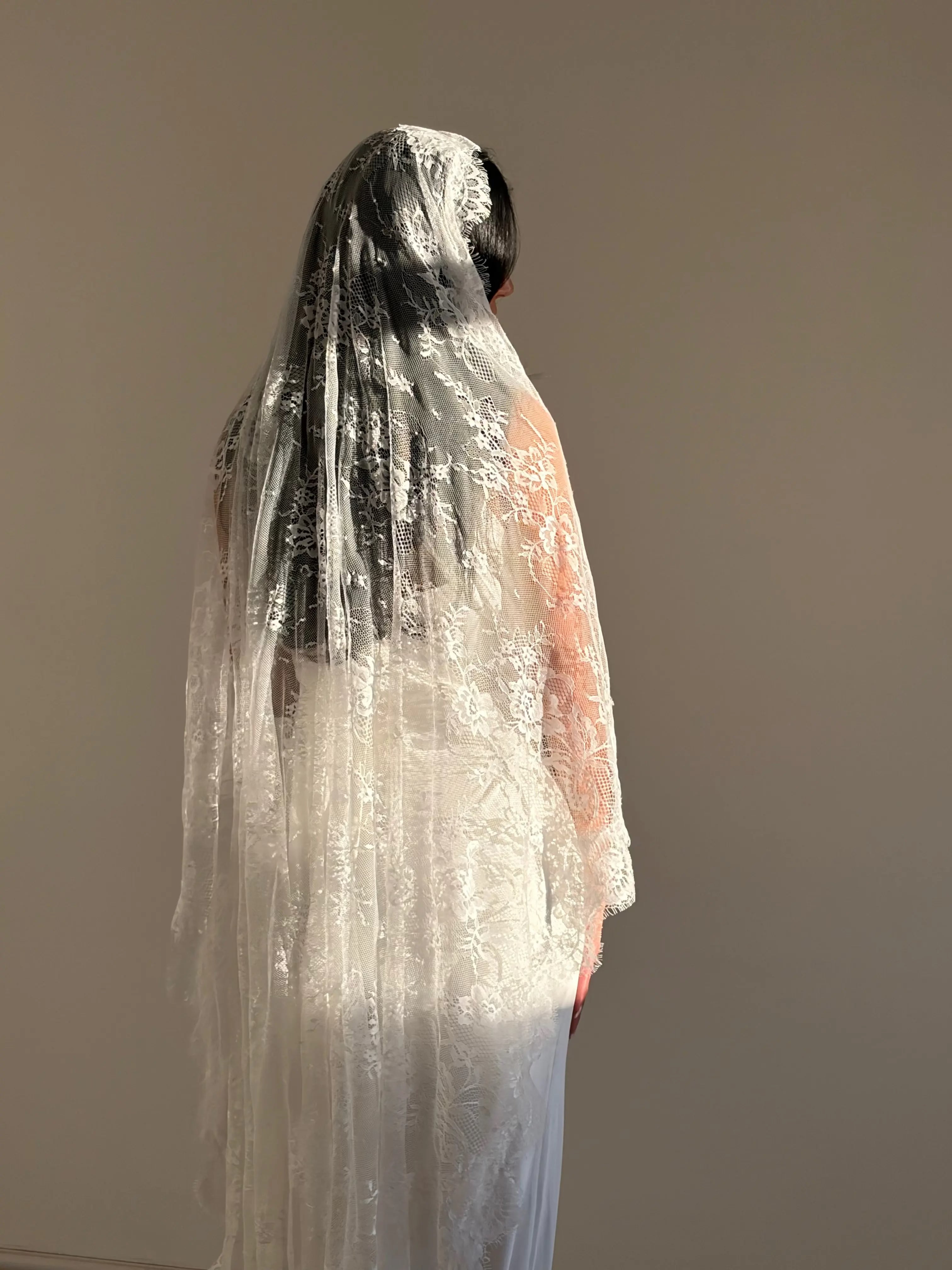 The Mantilla-Style Chantilly Rose Full Lace Veil is a cathedral-length bridal statement piece, designed for timeless elegance. Made from soft, lightweight tulle, it features intricate Chantilly rose lace that frames the veil completely, creating a delicate, romantic finish. The veil drapes beautifully straight to the ground, evoking a graceful, ethereal silhouette.This a vintage take on spanish style mantilla veil.